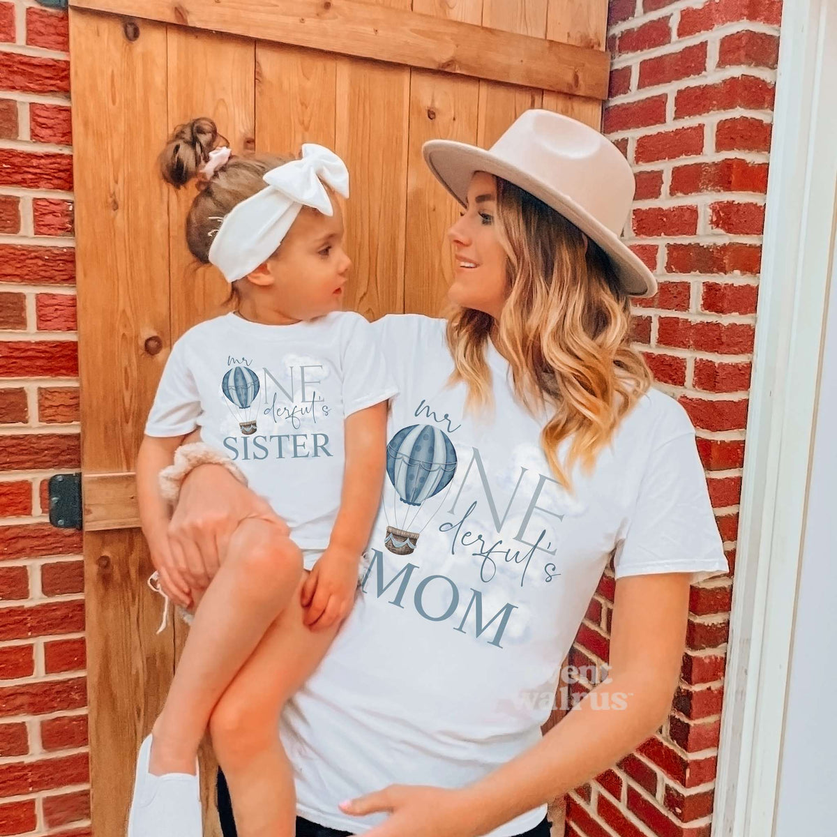 Mom holding her daughter by a barn door, both in white hot air balloon Mr Onederful shirts