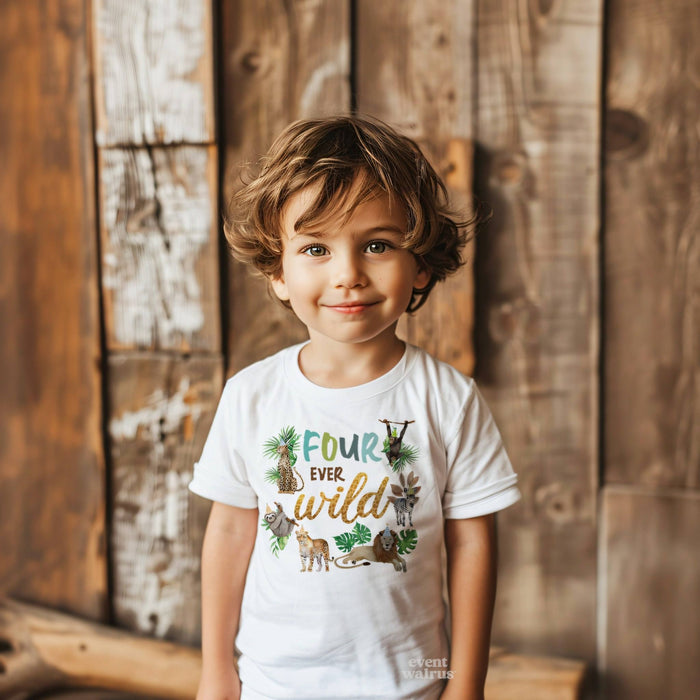 Smiling boy by a wood wall in a white Four Ever Wild birthday tee with jungle animals.
