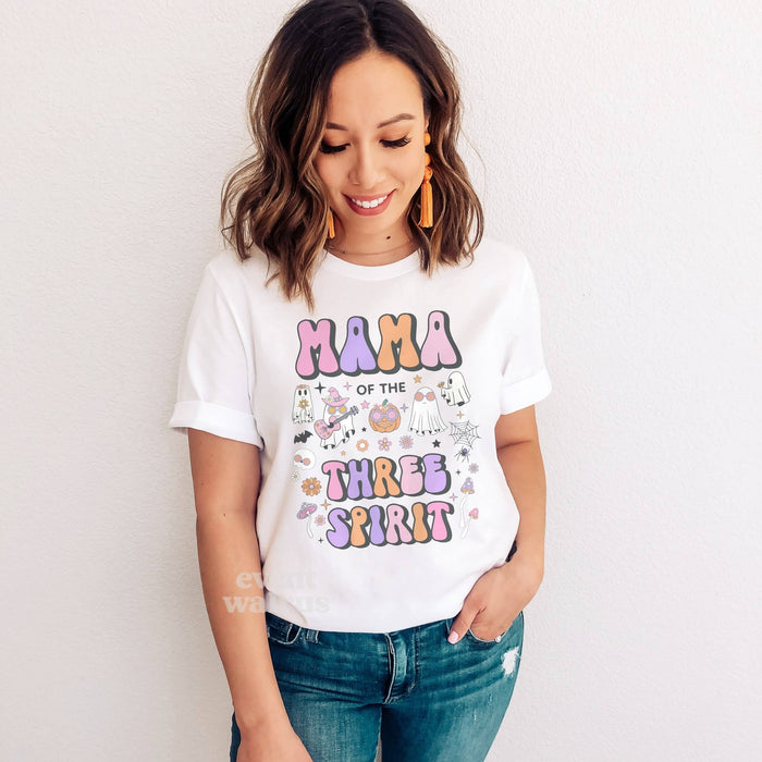 Smiling woman in jeans wearing a white Mama of the Three Spirit shirt.