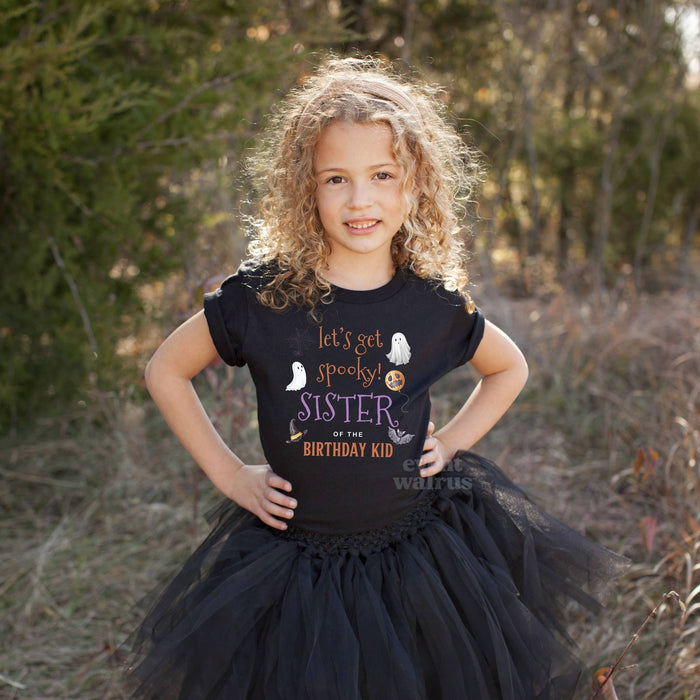 Curly haired girl in a black tutu wearing a Let's Get Spooky Sister of the Birthday Kid shirt.