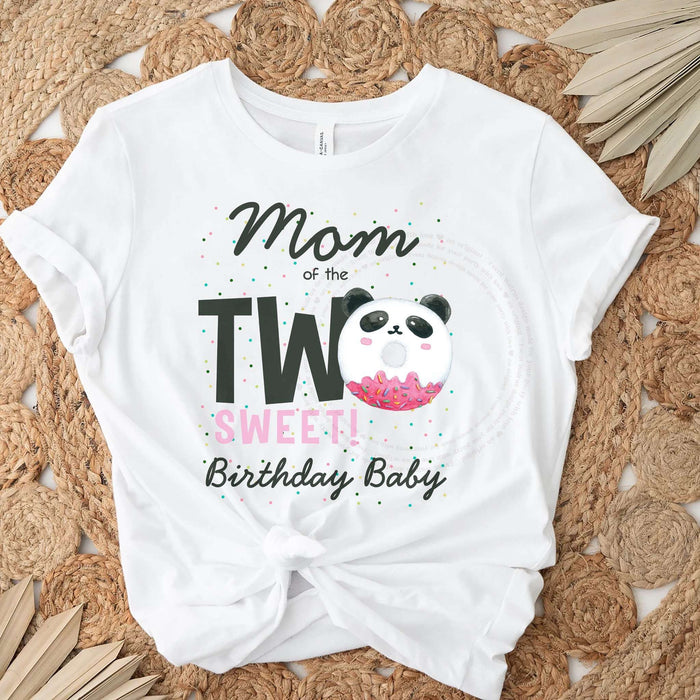White Mom of the Two Sweet panda donut tee laid flat on a jute rug with dried palm leaves.