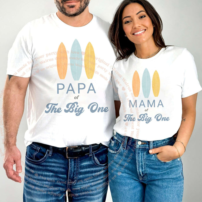 Couple in white Papa and Mama of The Big One shirts with three pastel surfboards.