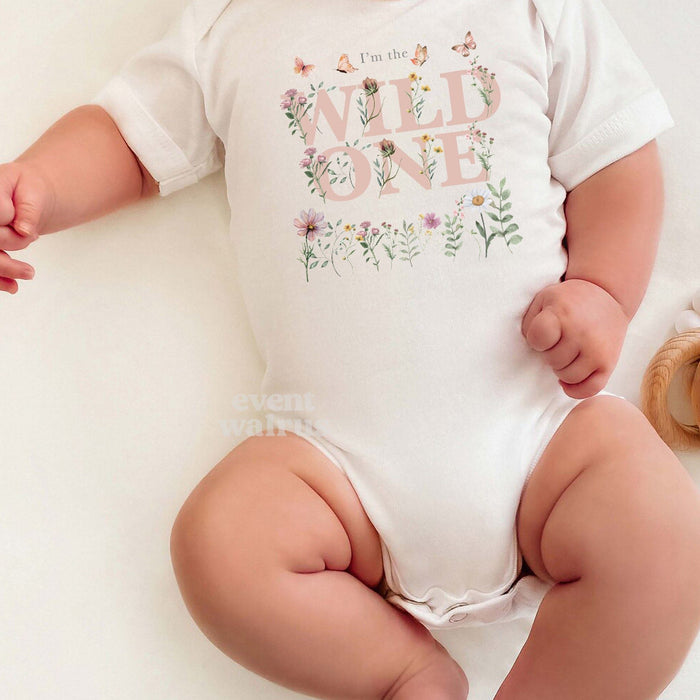 Baby in a white I'm the Wild One wildflower bodysuit for a first birthday.