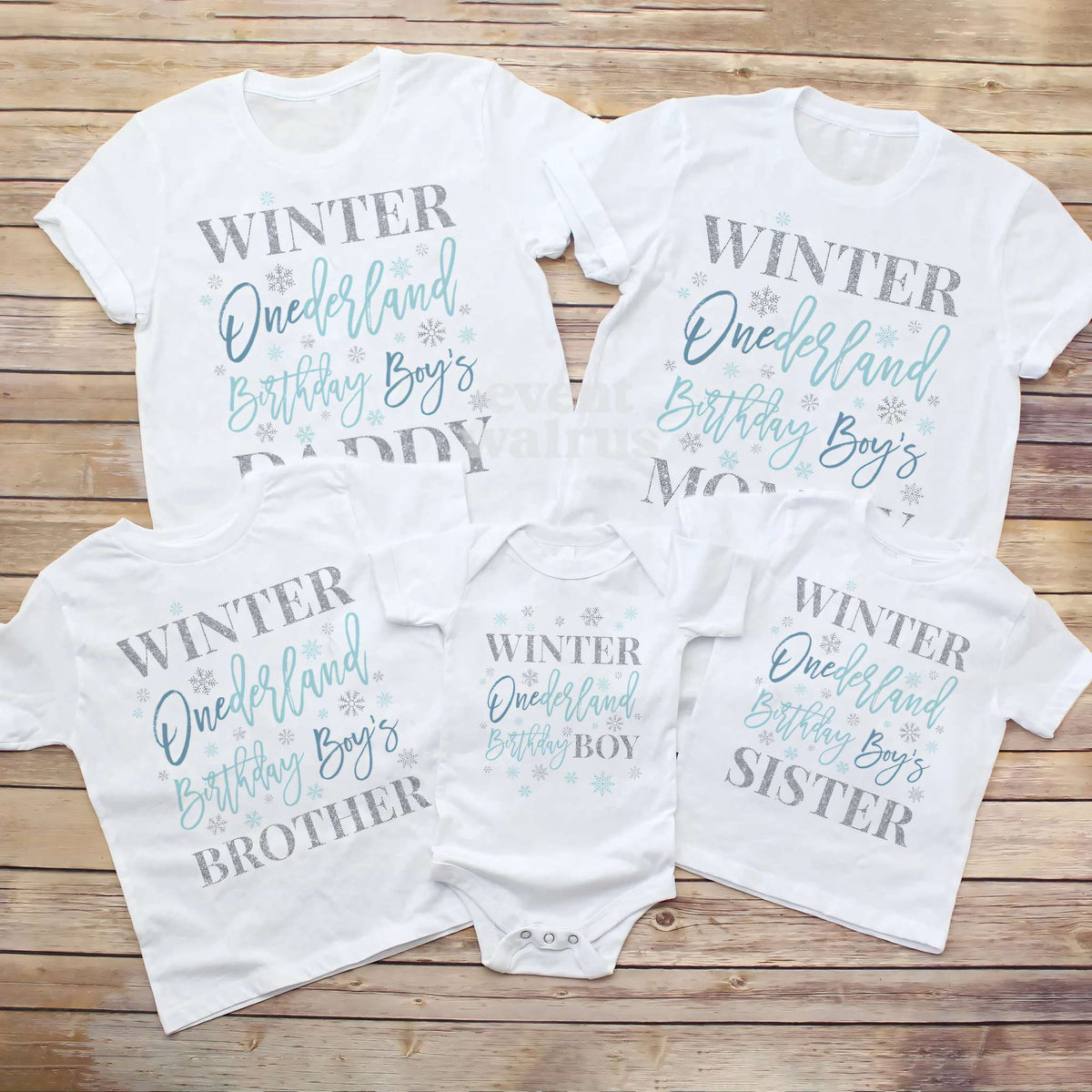 Blue and silver Winter Onederland Daddy, Mommy, Brother, Sister and Birthday Boy shirts laid out on wood