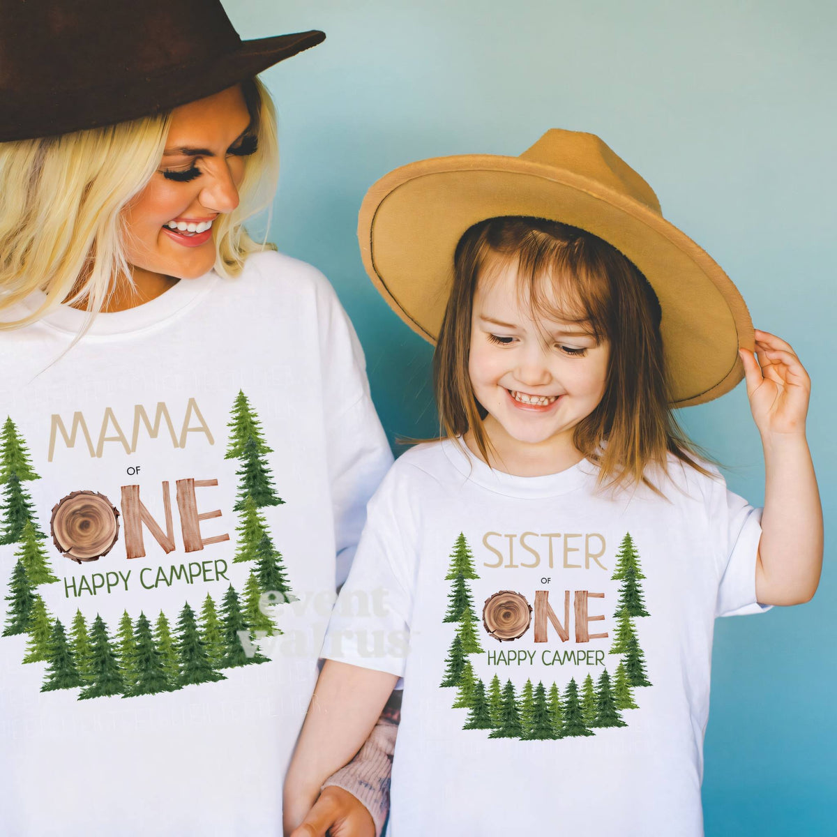 Mom and daughter in cowboy hats and white One Happy Camper shirts with a wood slice ONE and pine trees