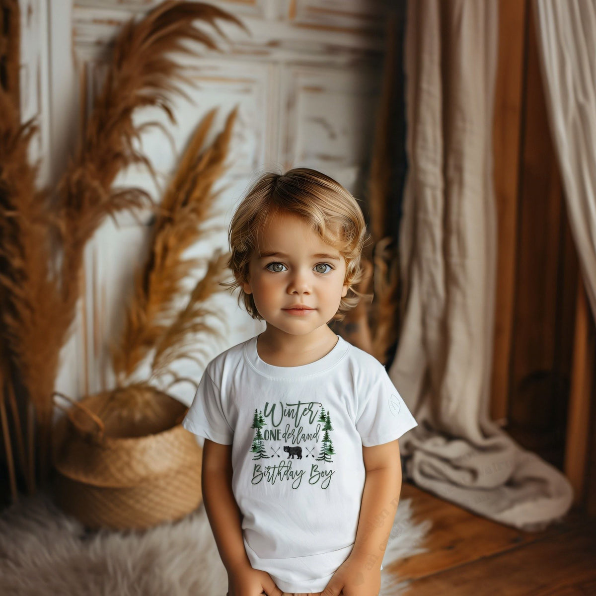 Toddler boy in a white Winter ONEderland Birthday Boy tee with the bear and pine trees.