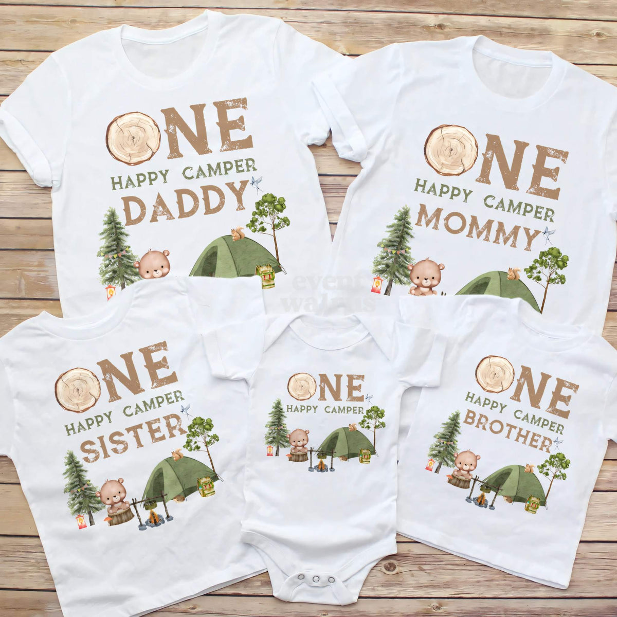 Daddy, Mommy, Sister, Brother and baby One Happy Camper shirts laid out on wood.