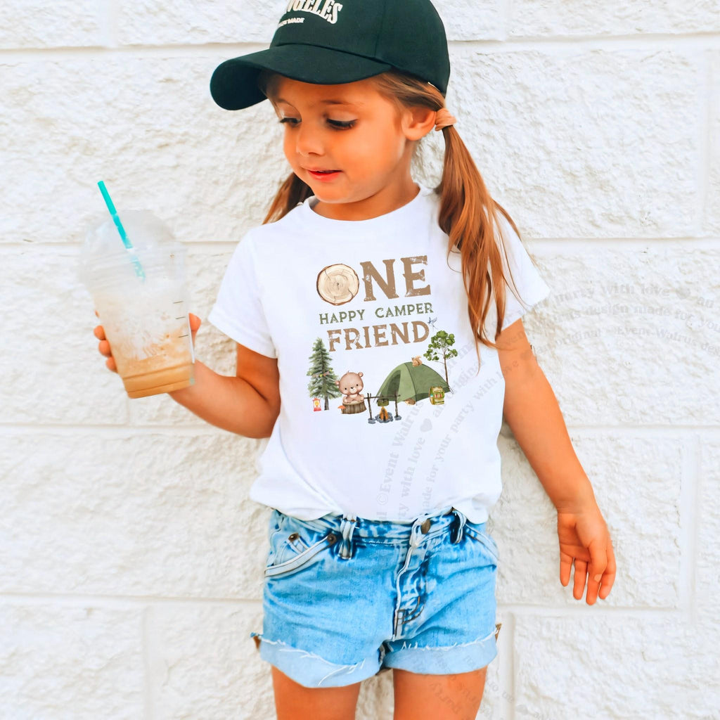 Girl in a ball cap holding a drink in a white One Happy Camper Friend shirt.