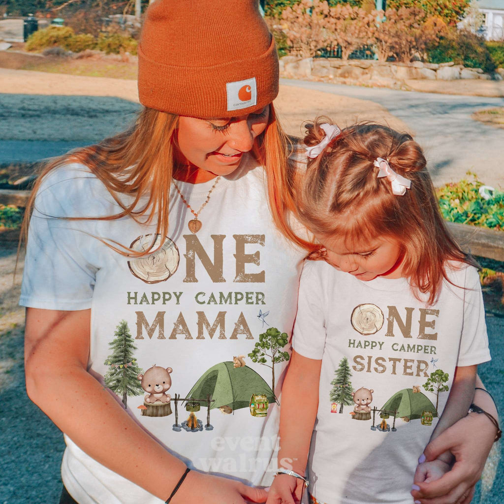 Mom in an orange beanie beside her daughter, both in white One Happy Camper shirts.