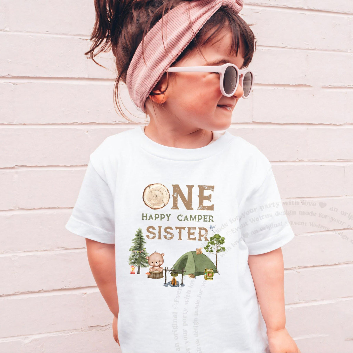 Girl in sunglasses and a pink headband wearing a white One Happy Camper Sister shirt.