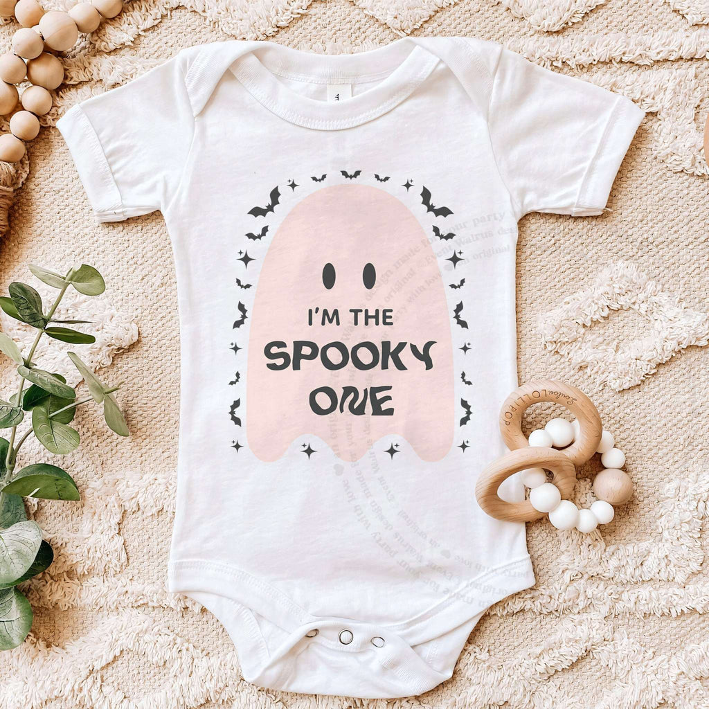 White Spooky One bodysuit on a beige blanket with a wooden teether.