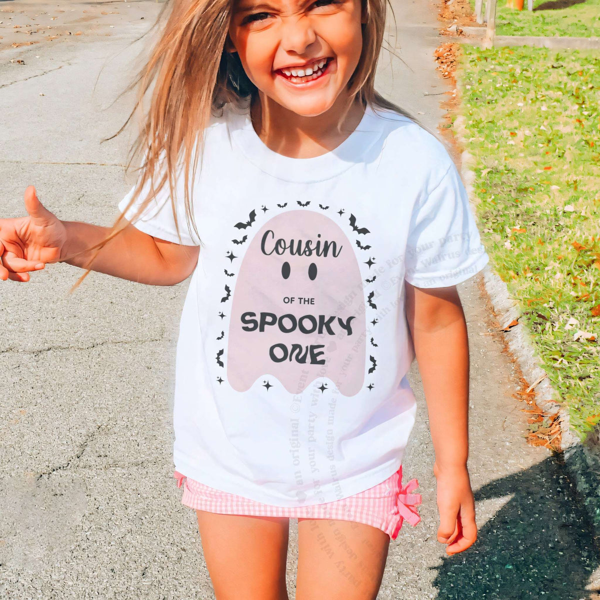 Laughing girl outdoors in a white Cousin of the Spooky One kids tee.