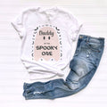 White Daddy of the Spooky One pink ghost tee laid flat beside jeans.