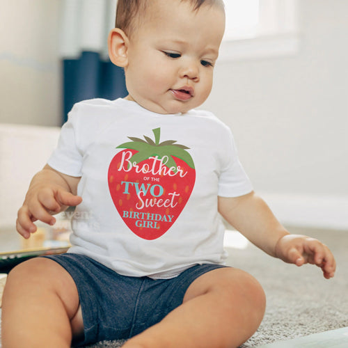 Baby boy sitting on a rug in a white Brother of the Two Sweet baby tee.