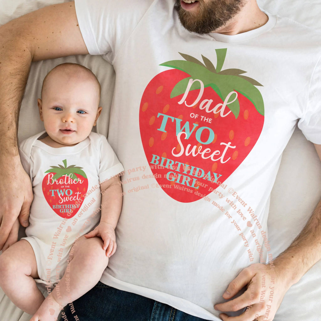 Dad lying with the baby in matching Dad and Brother big strawberry shirts.