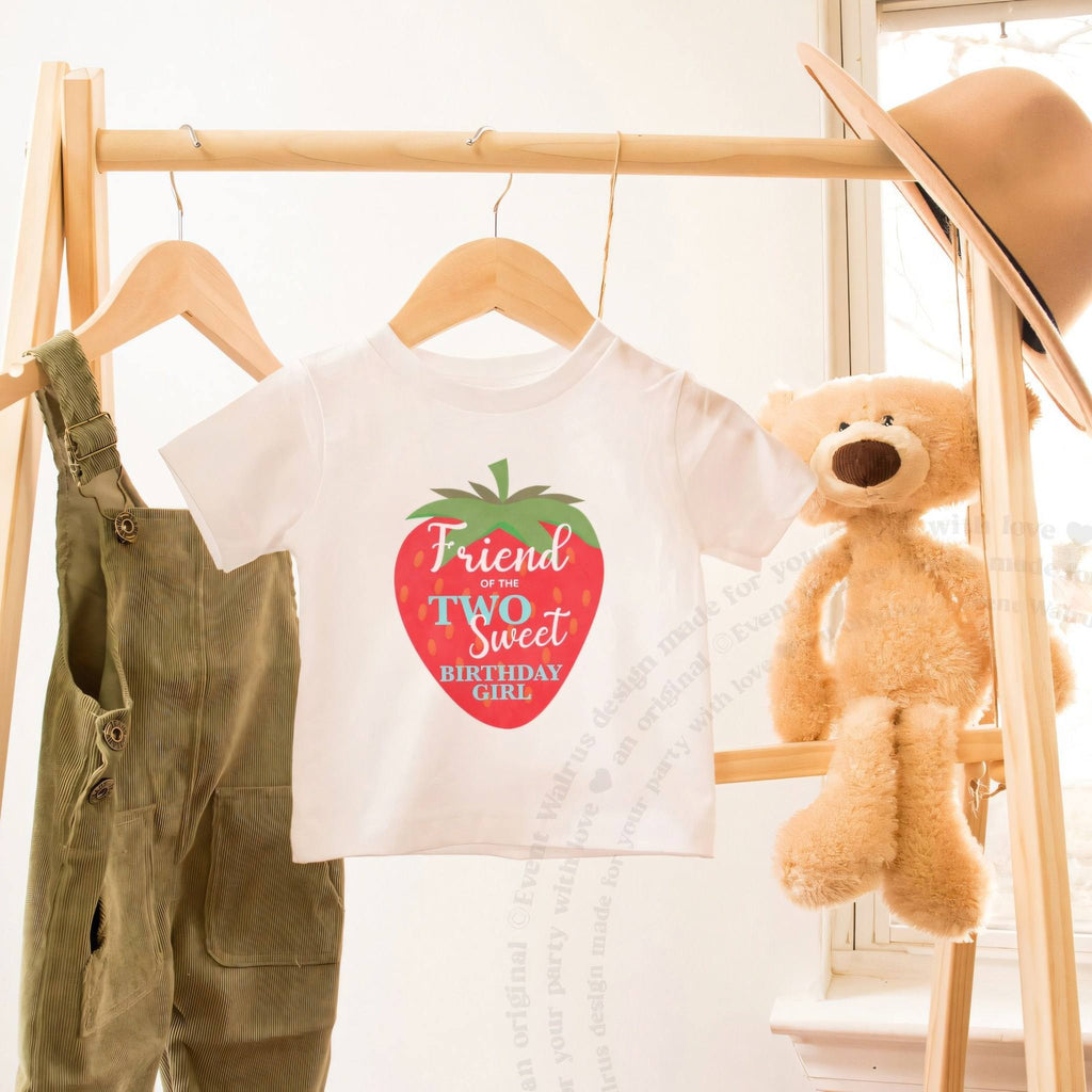 White Friend of the Two Sweet toddler tee on a wooden clothes rack beside a teddy bear.