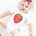 Baby girl with a pink bow lying in a white Sister of the Two Sweet bodysuit.