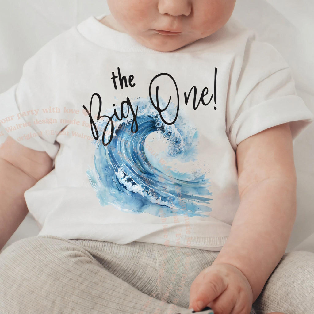 Baby in a white the Big One baby tee with a blue watercolor wave.