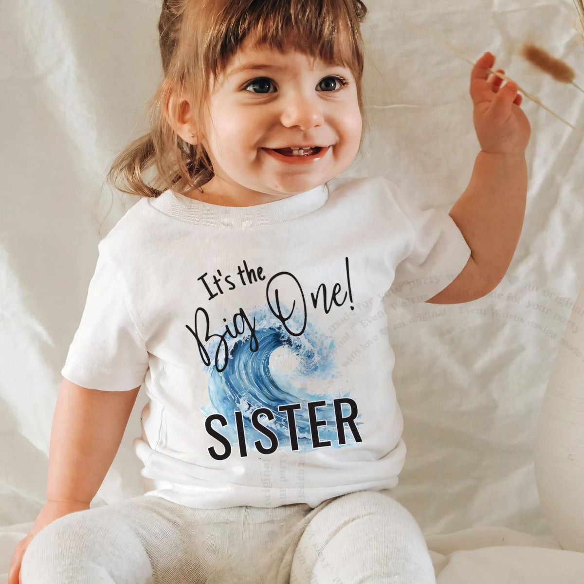 Smiling baby girl in a white It's the Big One Sister baby tee.