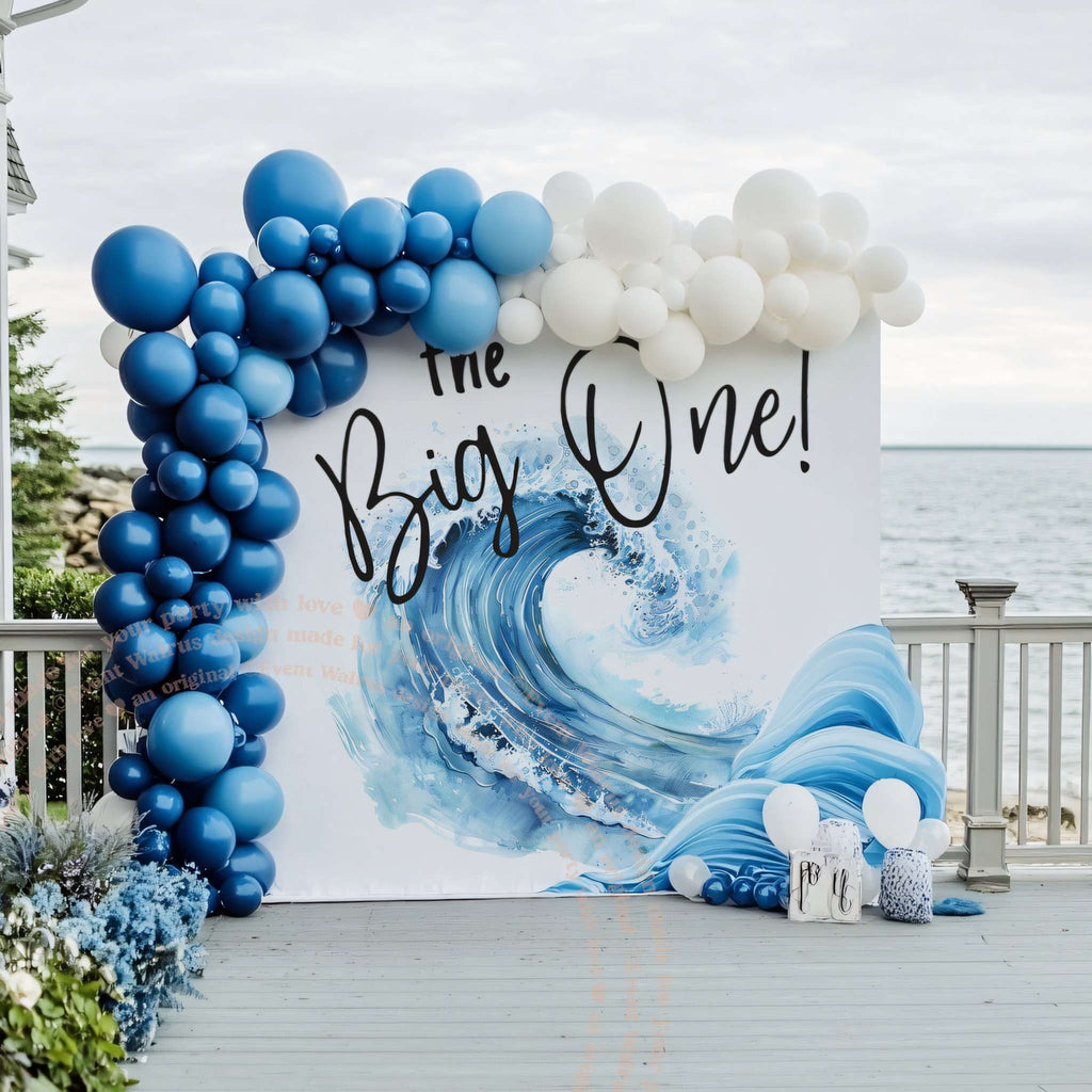 Crashing wave birthday backdrop with navy and white balloons on a seaside deck.