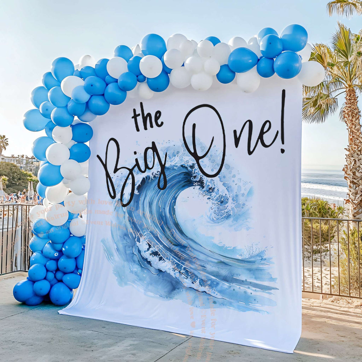The Big One wave backdrop on a deck over the ocean with blue balloons.