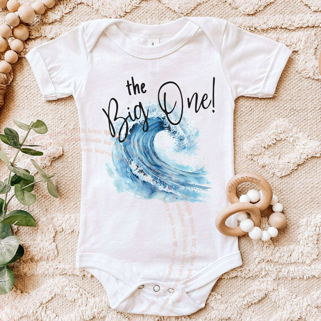 White the Big One bodysuit with a crashing wave, laid flat with a wooden teether.