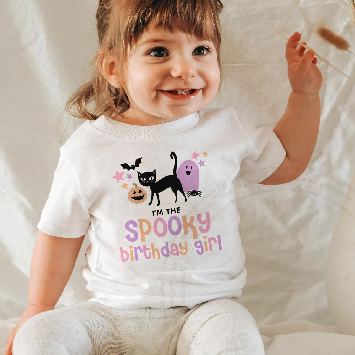 Laughing baby girl in a white I'm the Spooky Birthday Girl baby tee.