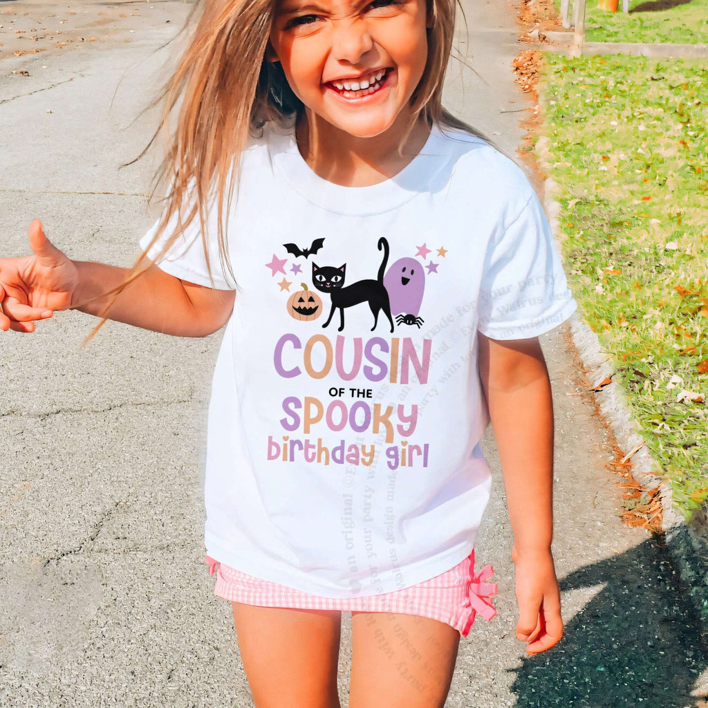 Laughing girl outdoors in a white Cousin of the Spooky Birthday Girl kids tee.