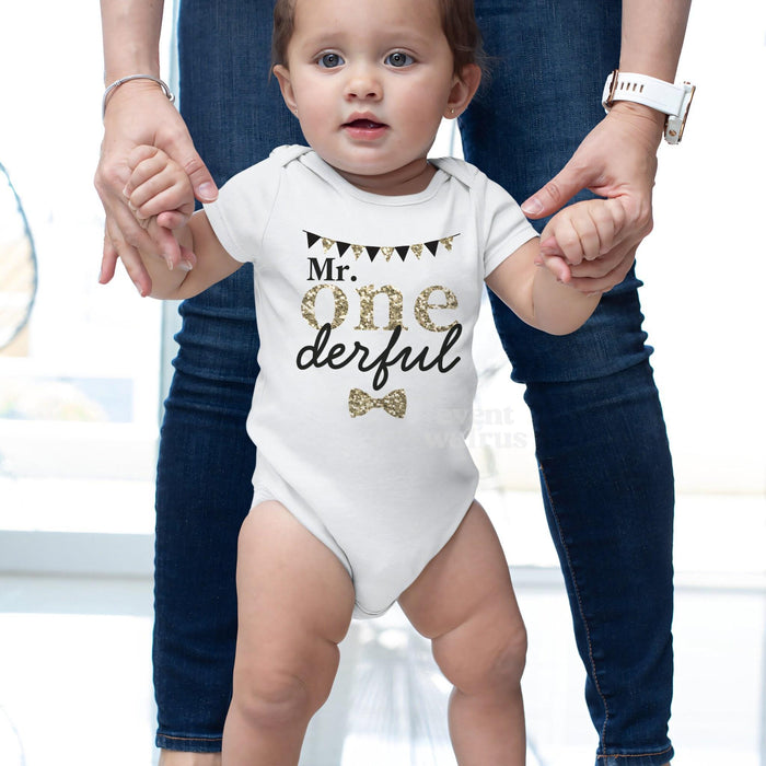 Baby taking steps while holding Mom's hands, in a white Mr Onederful bodysuit.
