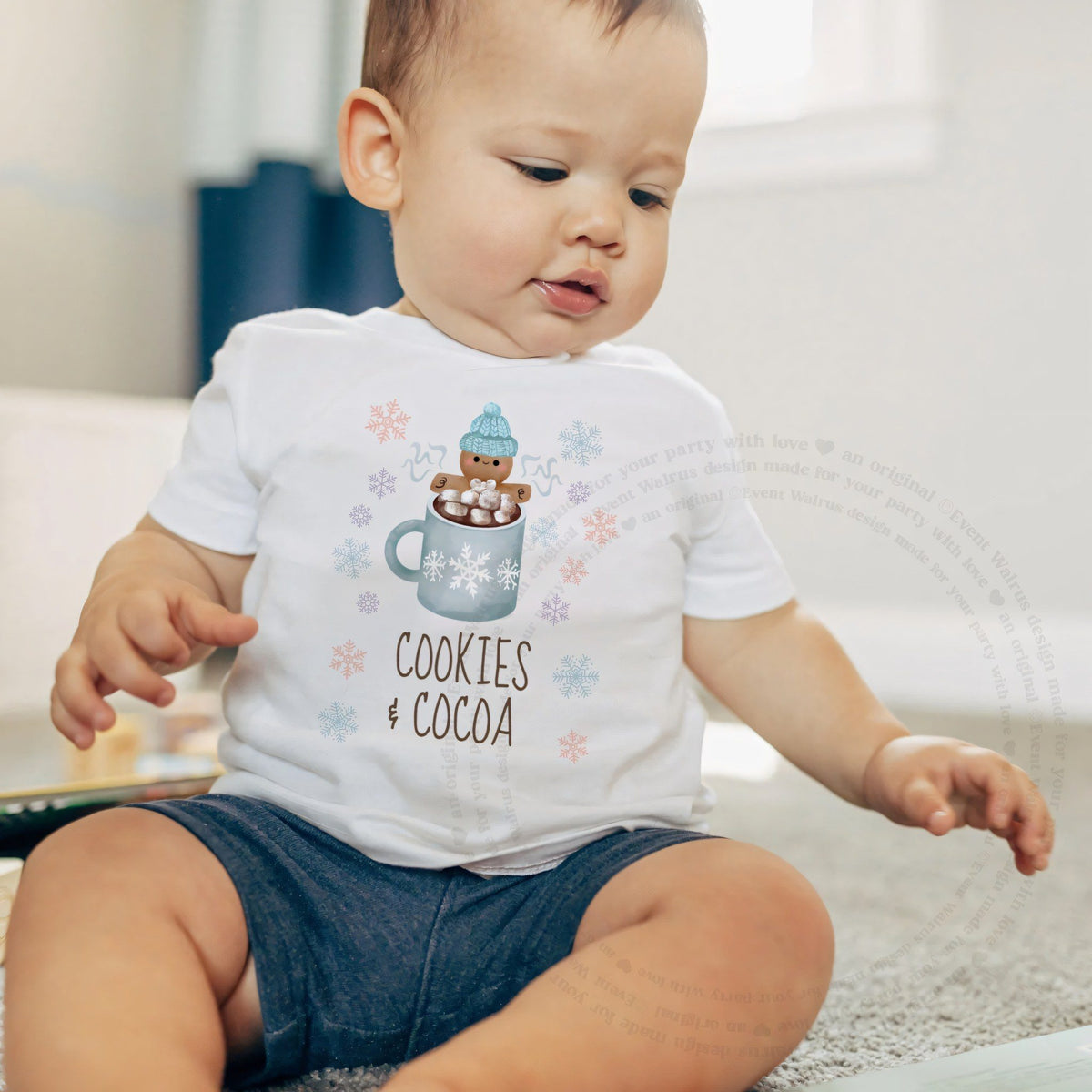 Baby boy sitting on a rug in a white Cookies and Cocoa baby tee.