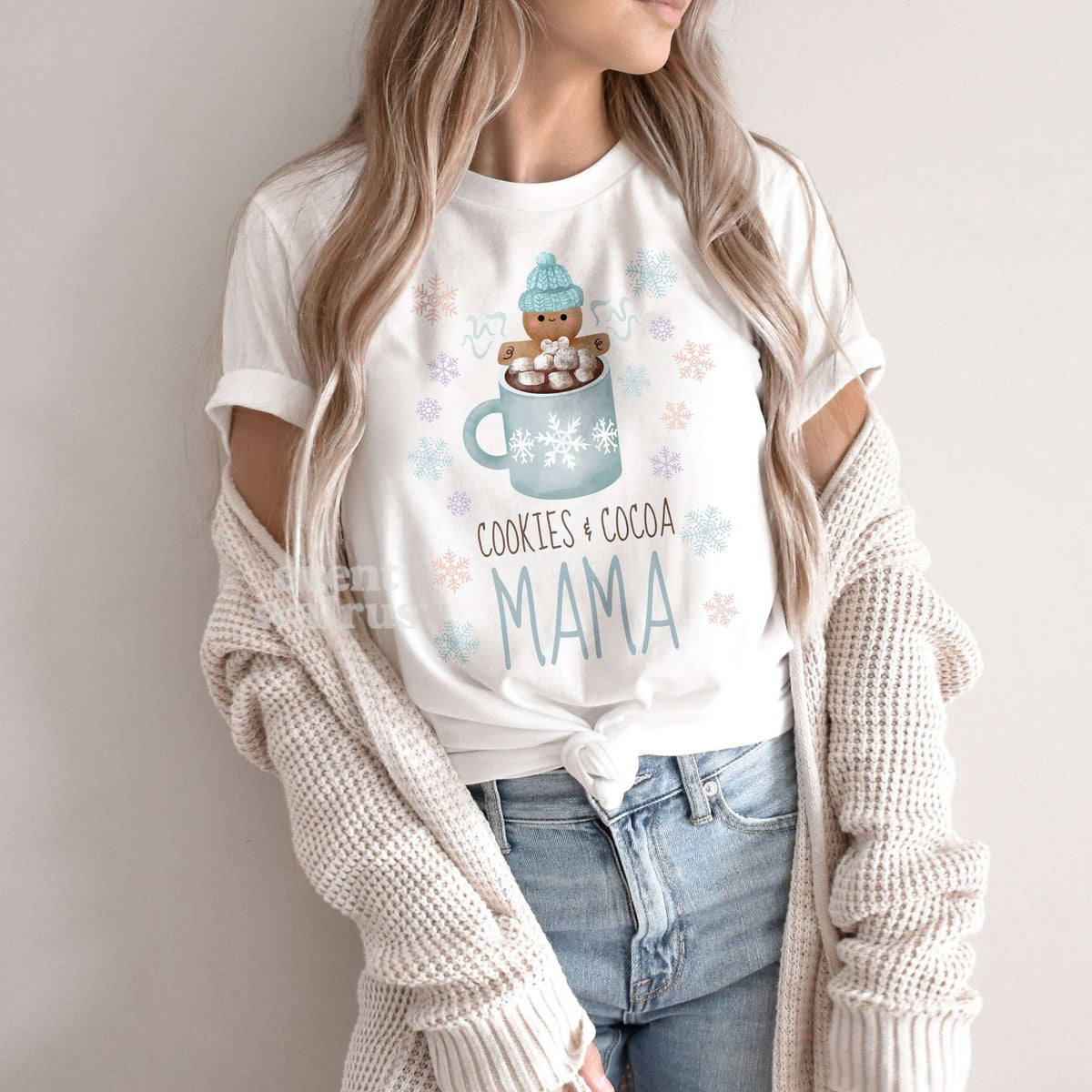 Woman in a knit cardigan wearing a white Cookies and Cocoa Mama shirt.