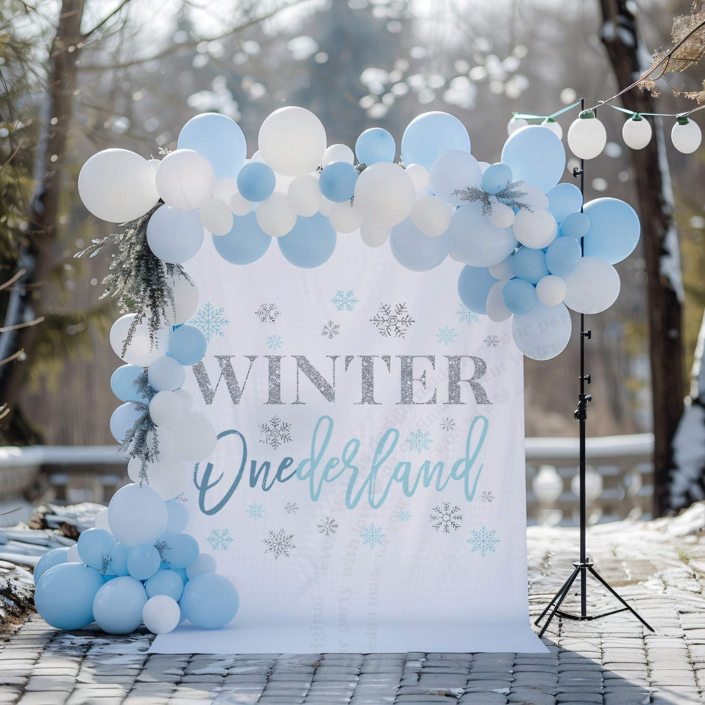 Winter onederland backdrop for a boy on a snowy patio with pale blue and white balloons.