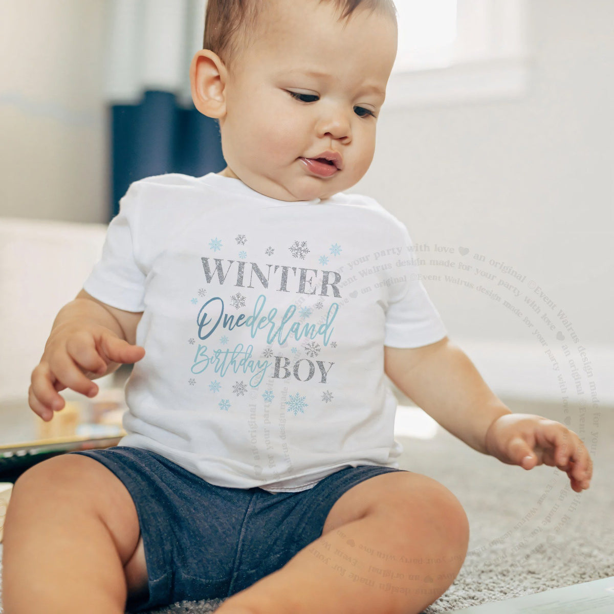 Baby boy sitting on a rug in a white Winter Onederland Birthday Boy baby tee.
