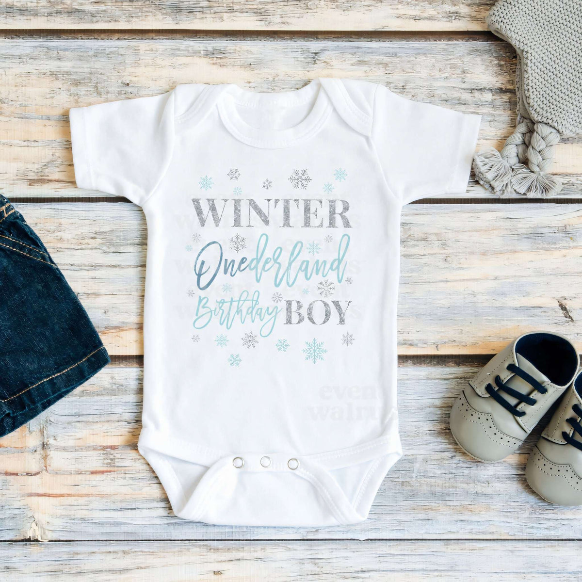 White Winter Onederland Birthday Boy bodysuit on weathered wood with denim shorts and sneakers.