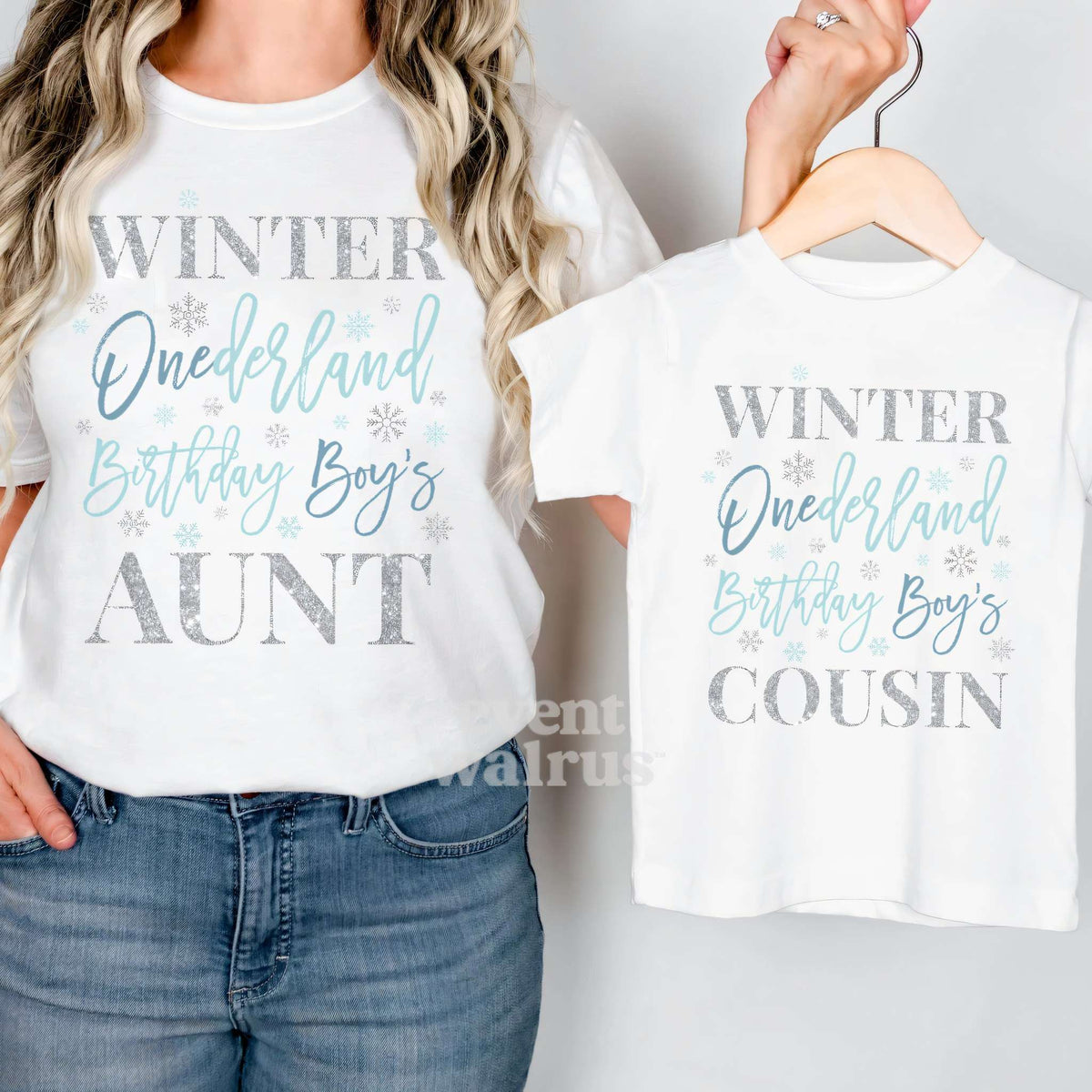 Aunt holding up a white Cousin Winter Onederland tee on a hanger while wearing her own.