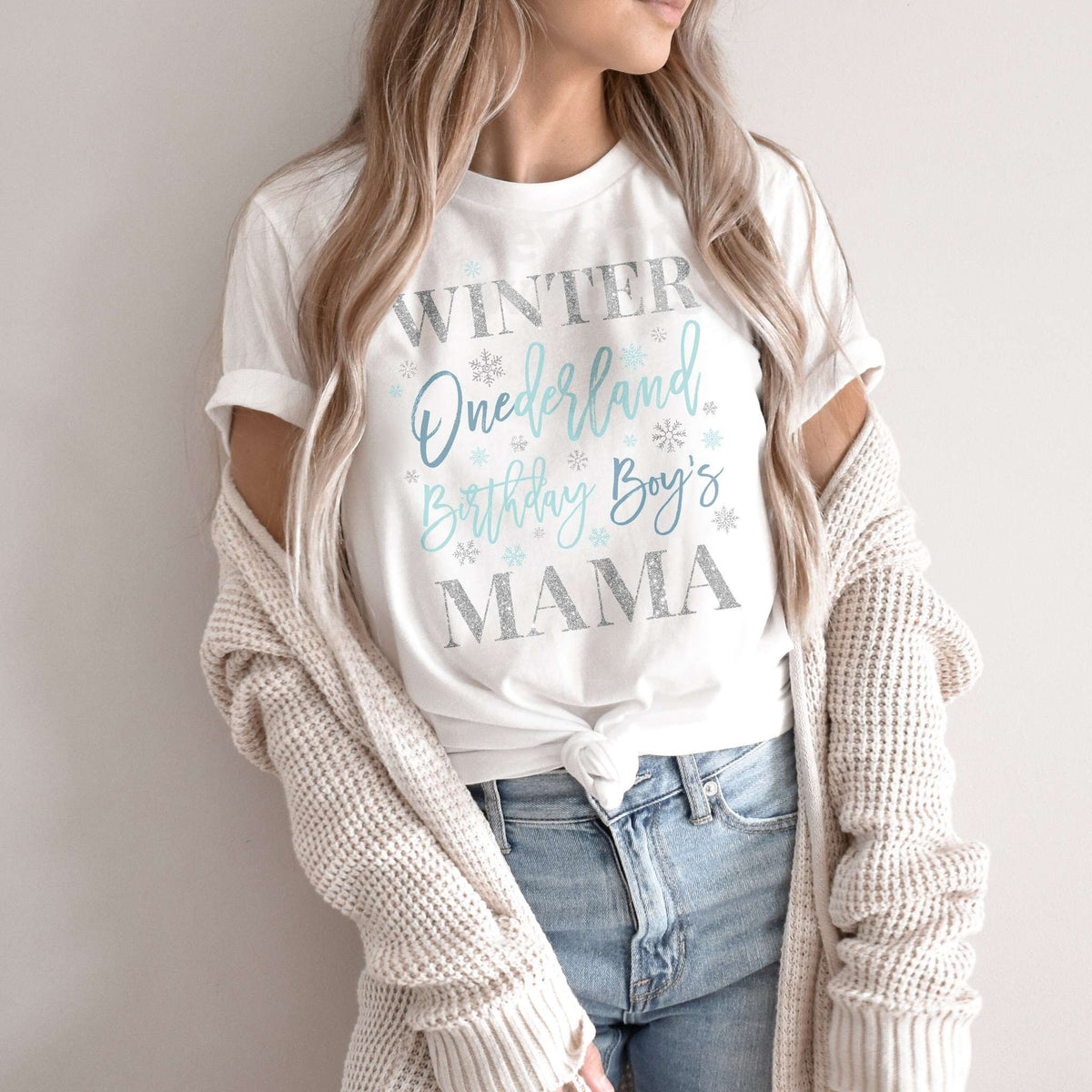 Woman in a knit cardigan wearing a white blue and silver Winter Onederland Mama shirt.