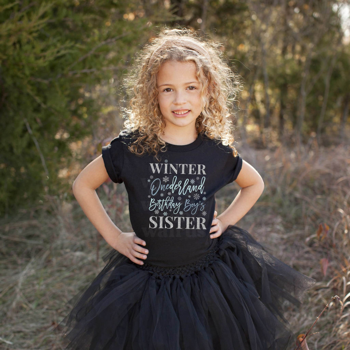 Girl in a black tutu and a black Winter Onederland Sister shirt in a field.