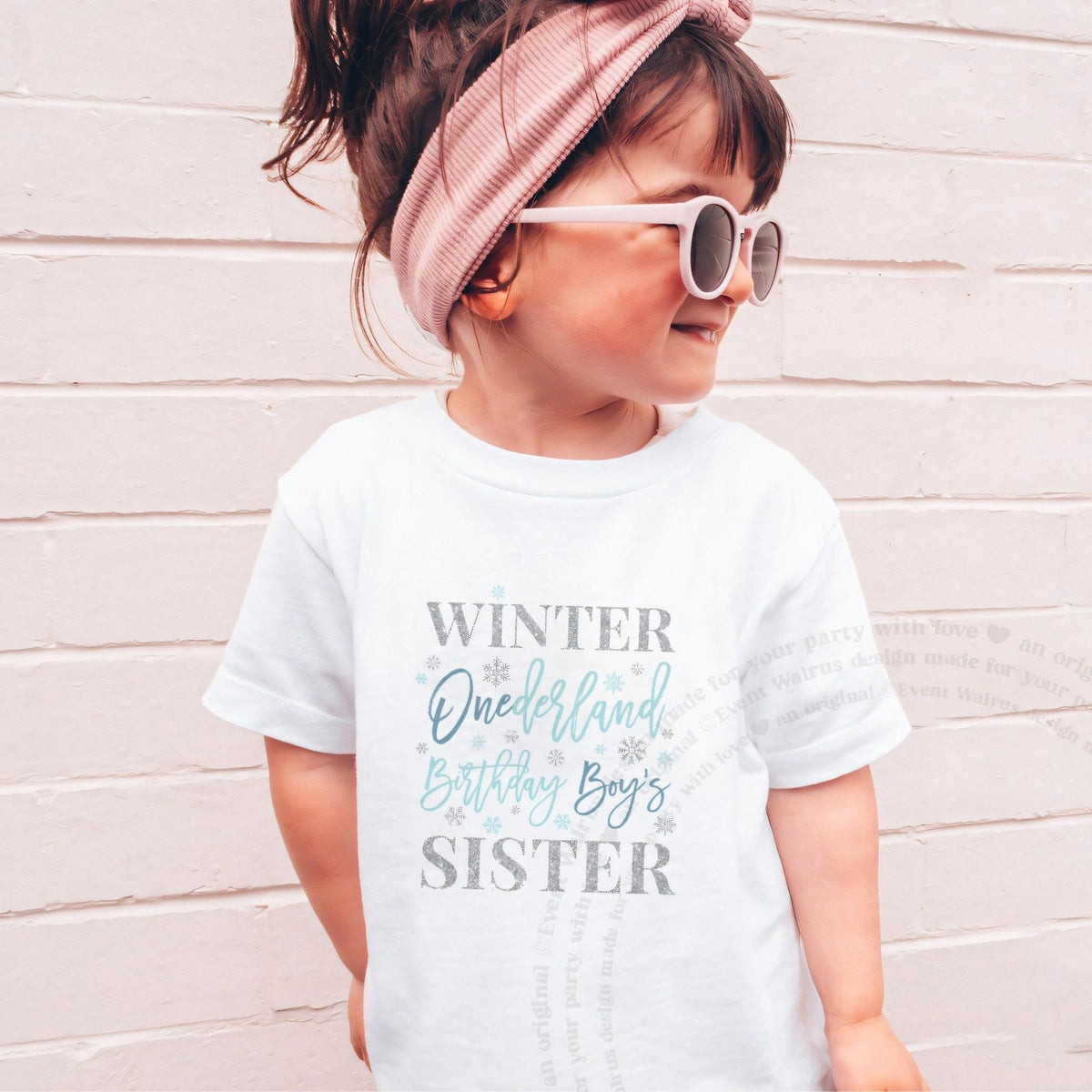 Girl in sunglasses and a pink headband wearing a white blue Winter Onederland Sister shirt.
