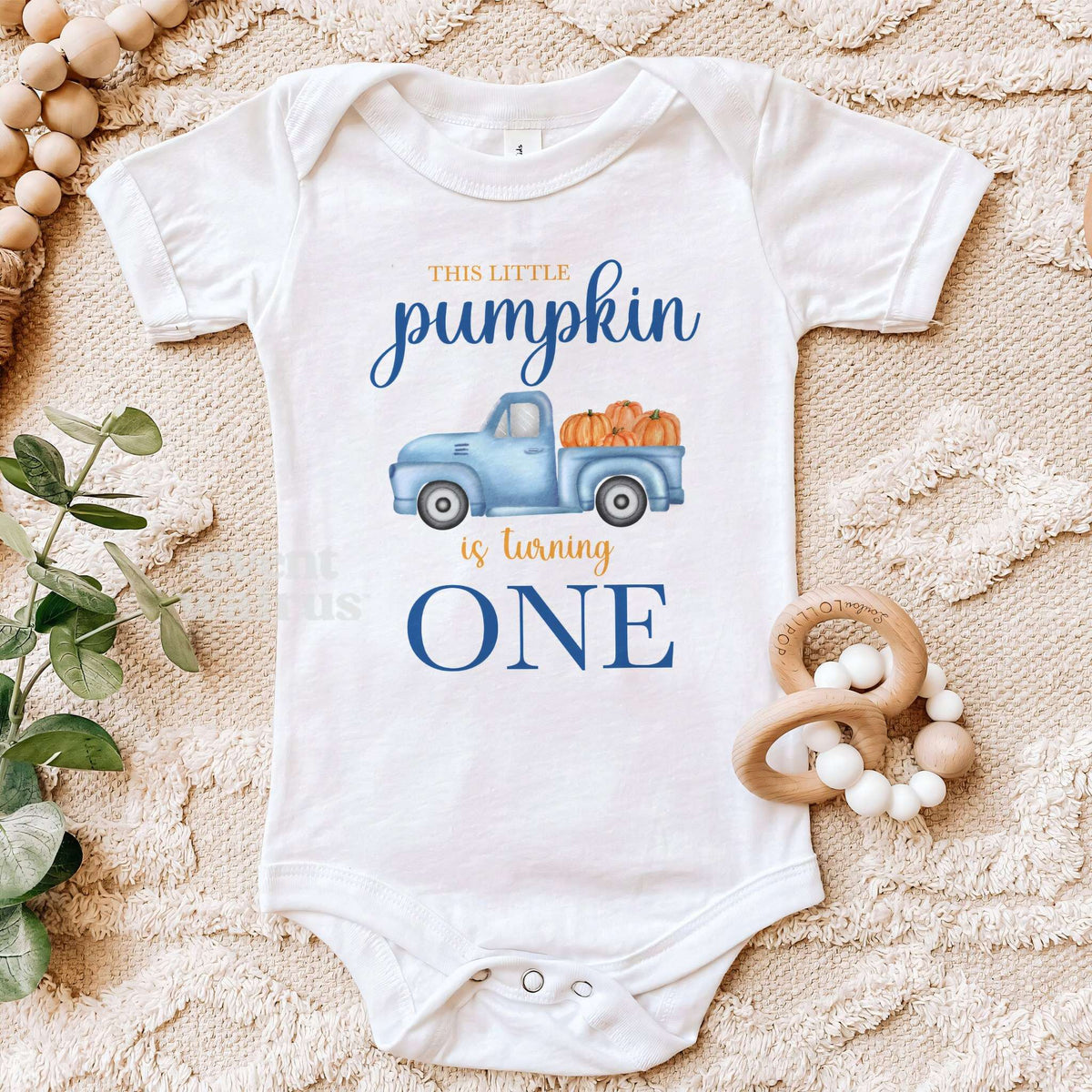 White blue truck Little Pumpkin bodysuit on a beige blanket with a wooden teether.