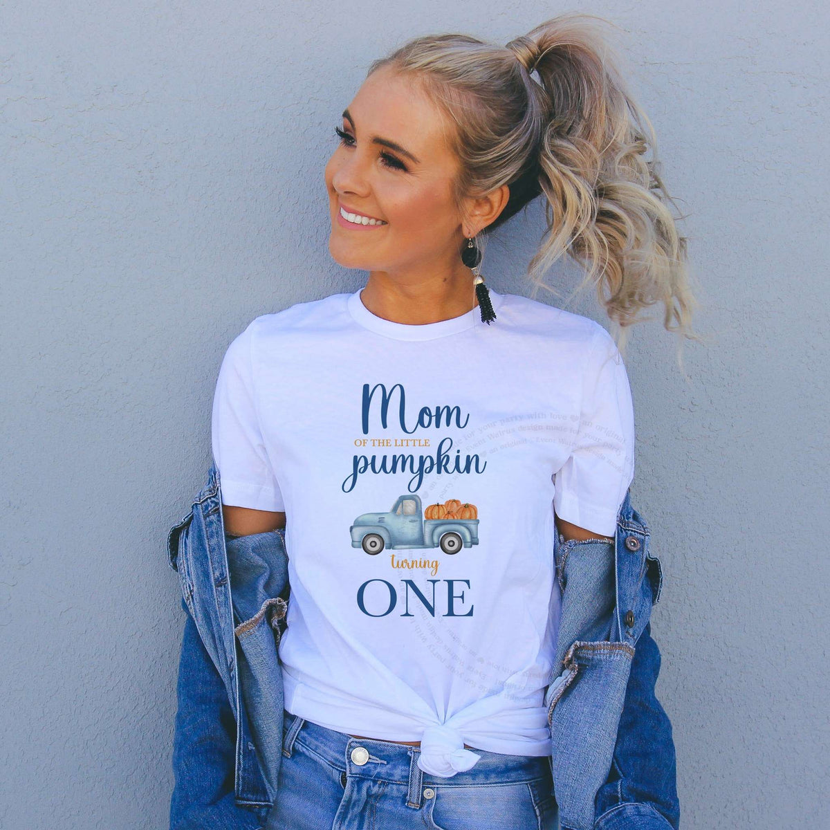 Woman in a denim jacket wearing a Mom of the Little Pumpkin shirt with a blue pumpkin truck.