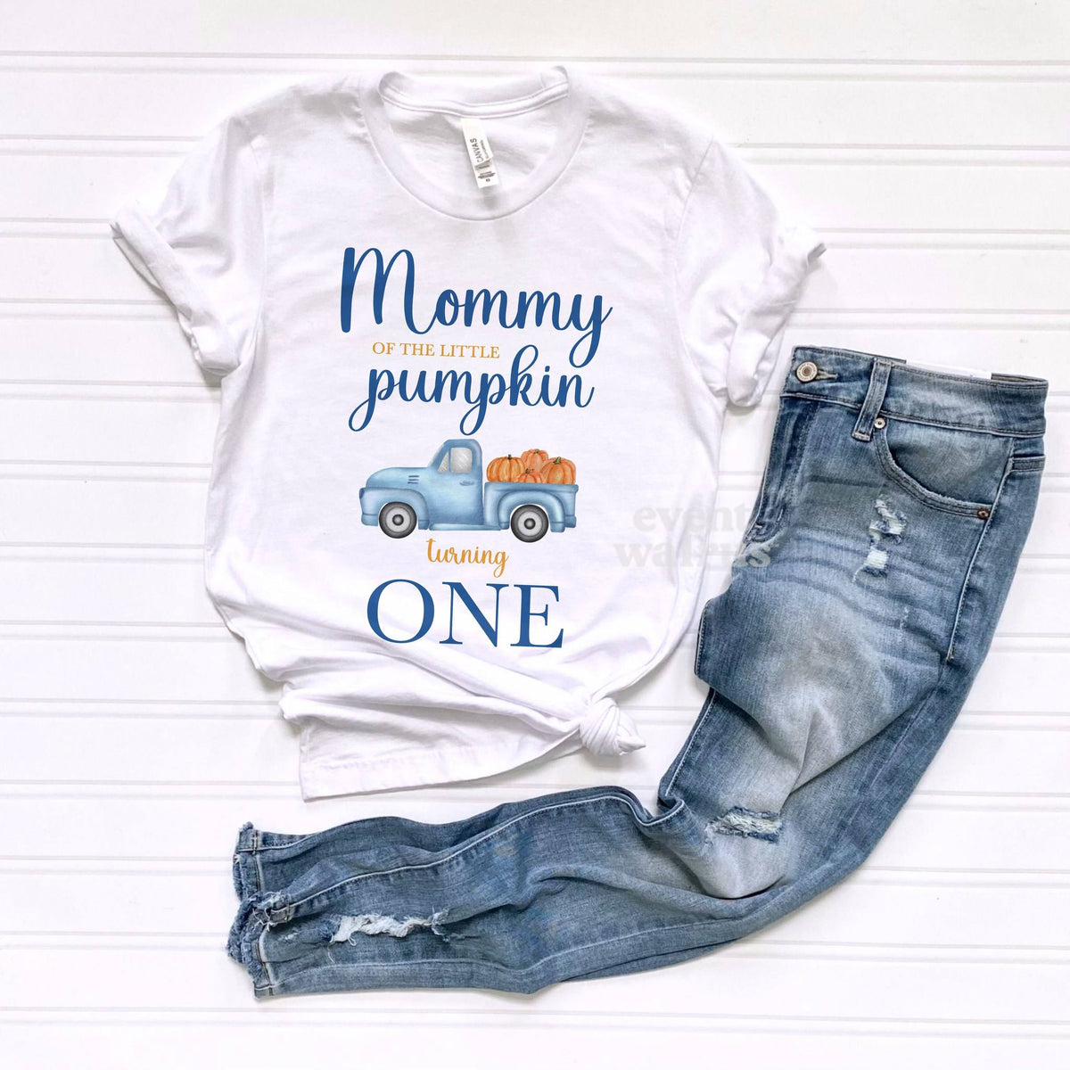 White Mommy of the Little Pumpkin tee laid flat beside ripped jeans.