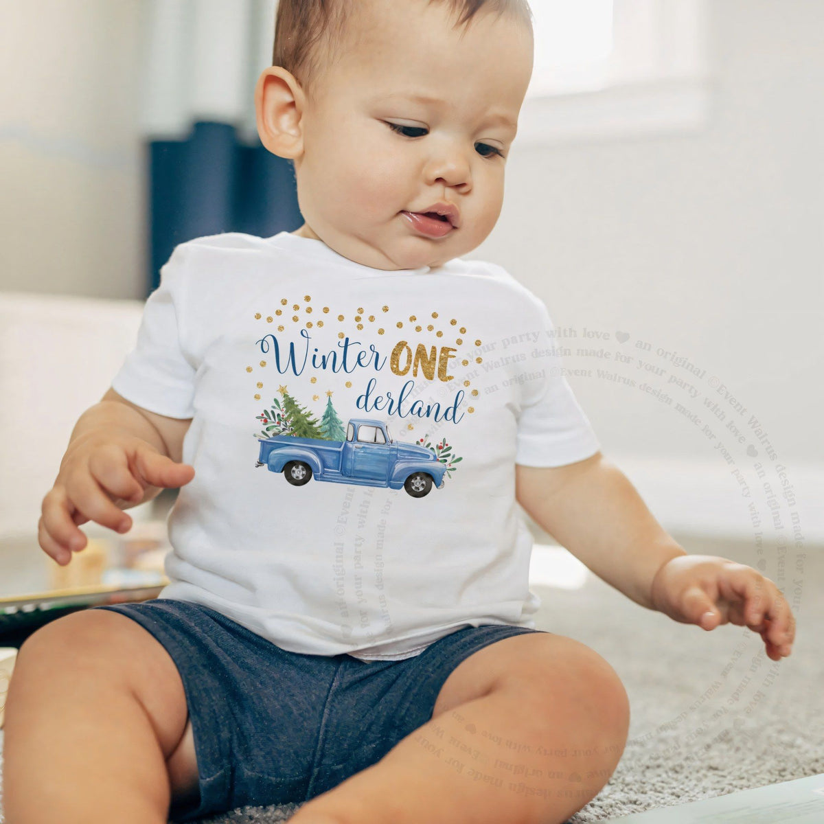 Baby boy sitting on a rug in a white blue truck Winter ONE derland baby tee.