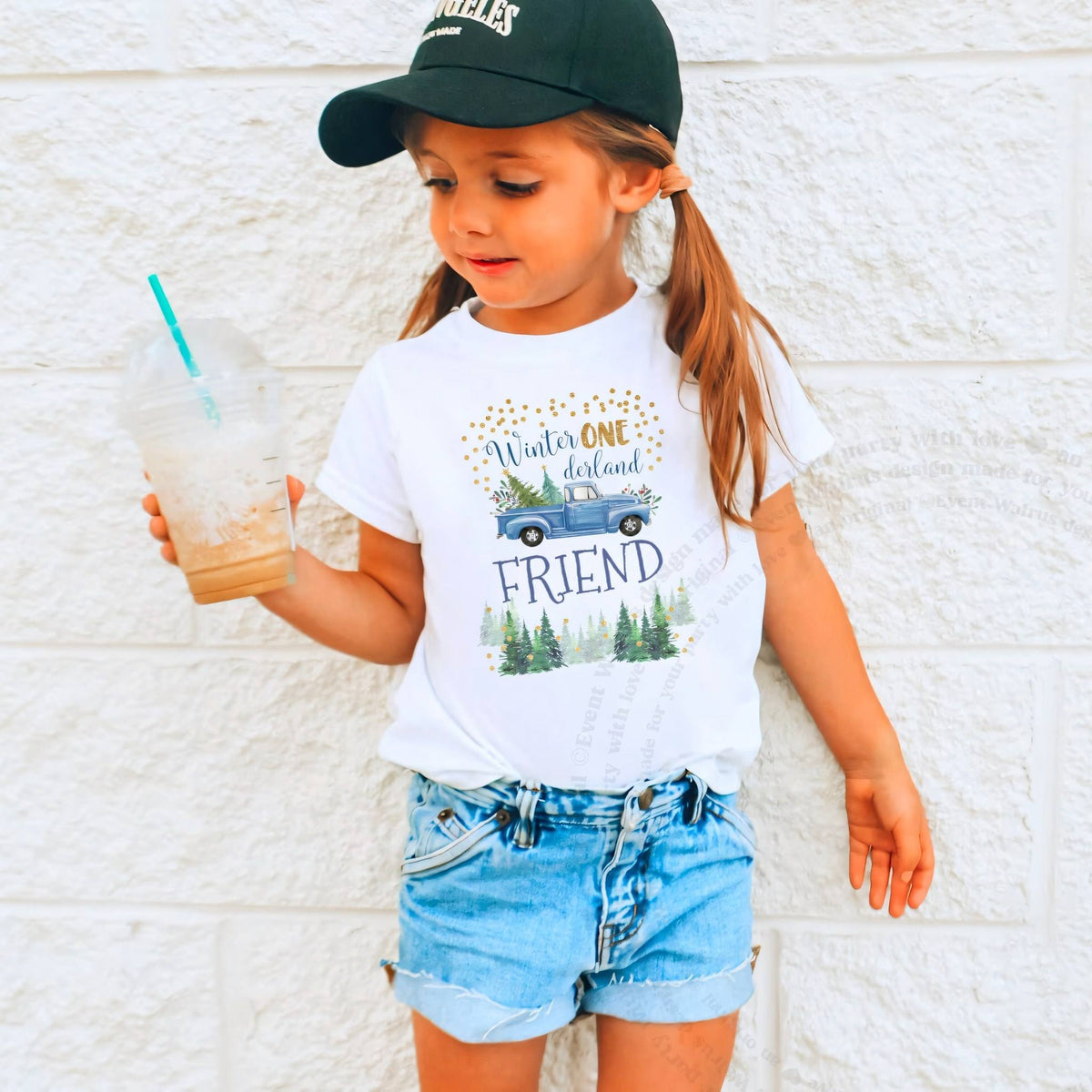 Girl in a ball cap holding a drink in a white blue truck Winter ONE derland Friend shirt.