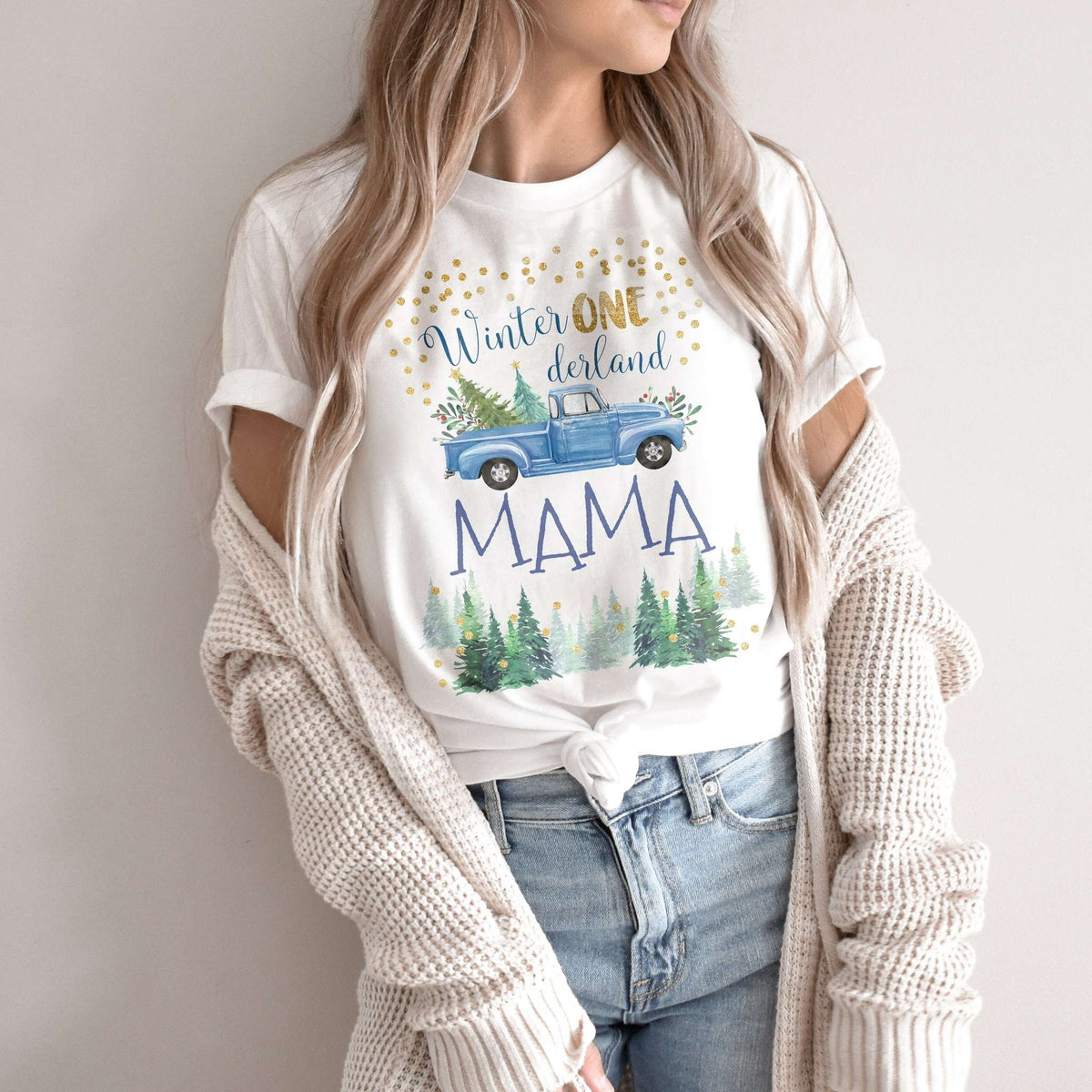 Woman in a knit cardigan wearing a white blue truck Winter ONE derland Mama shirt.