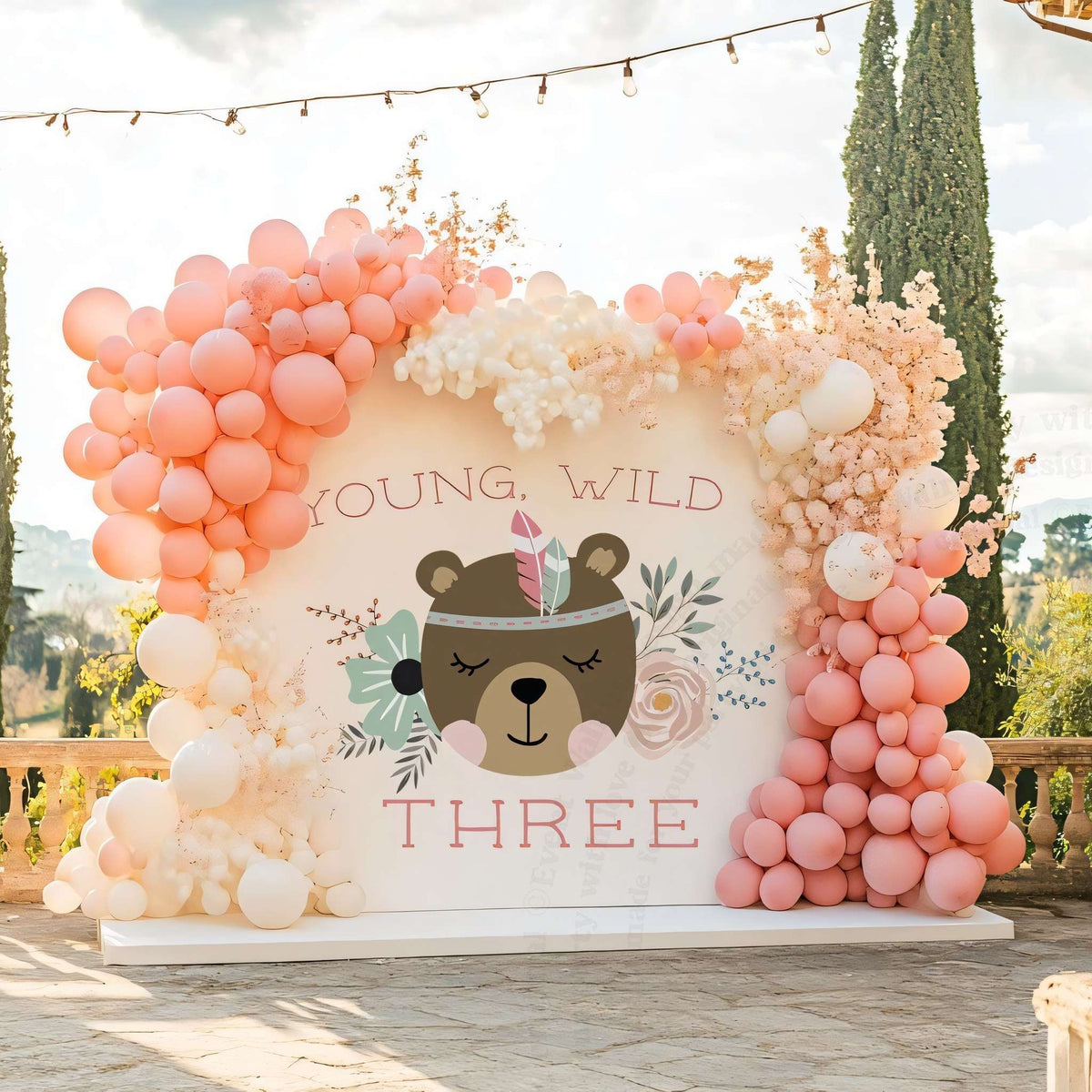 Young wild and three bear backdrop on a stone terrace with peach and cream balloons.