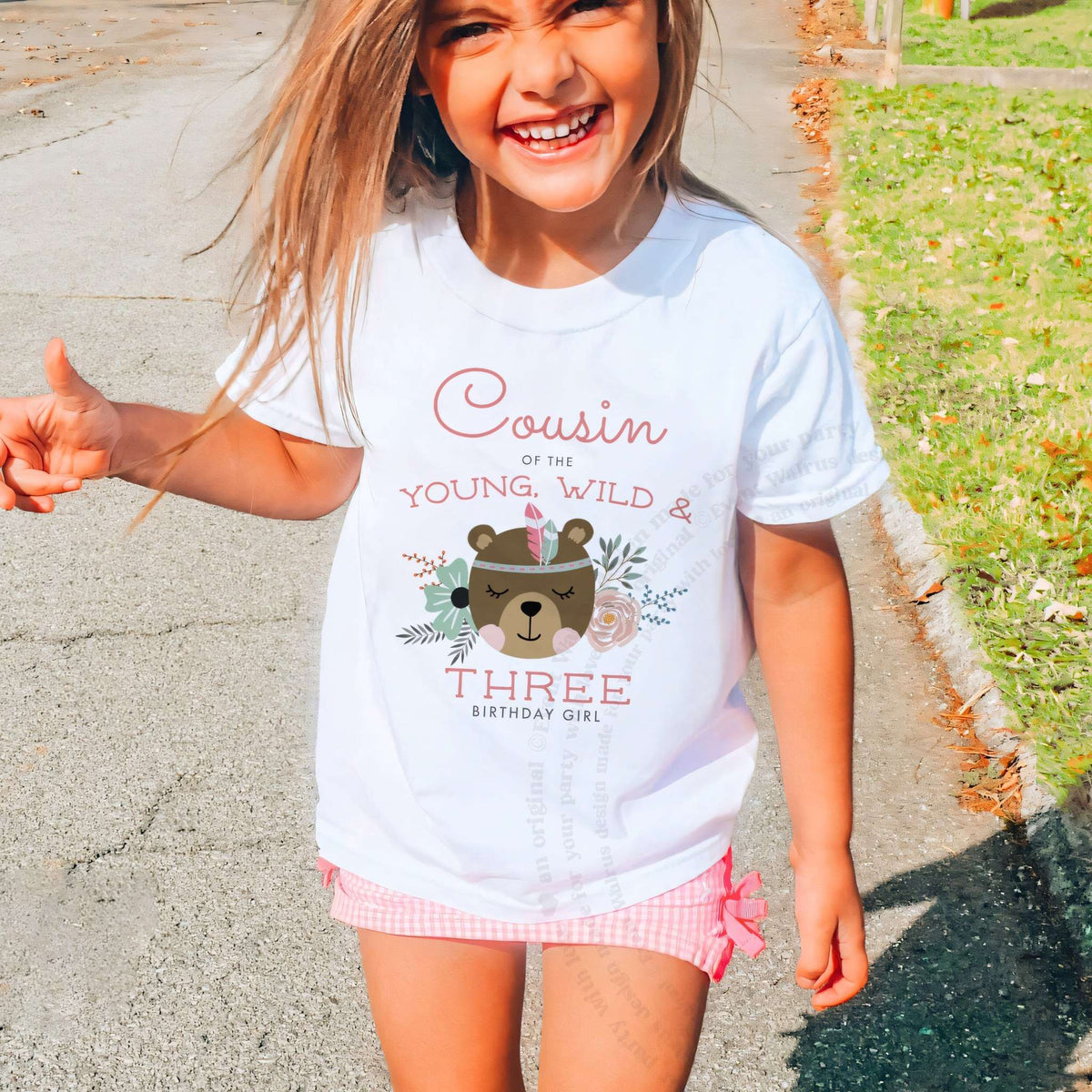 Laughing girl outdoors in a white Cousin of the Young, Wild and Three kids tee.