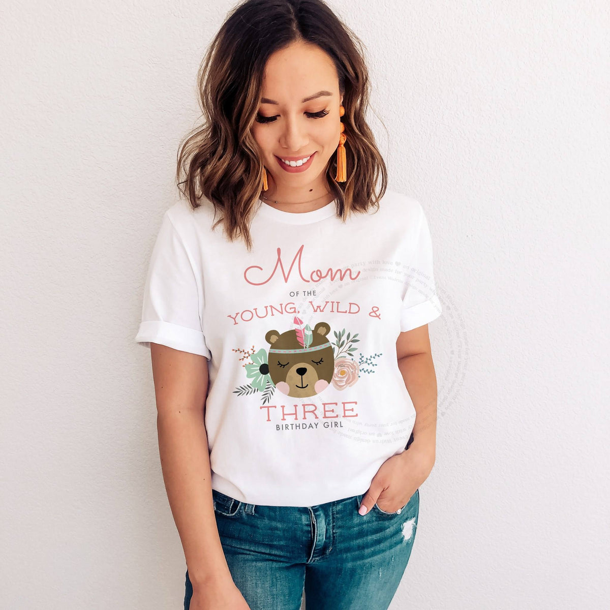 Smiling woman in jeans wearing a Mom of the Young, Wild and Three shirt with the boho bear.