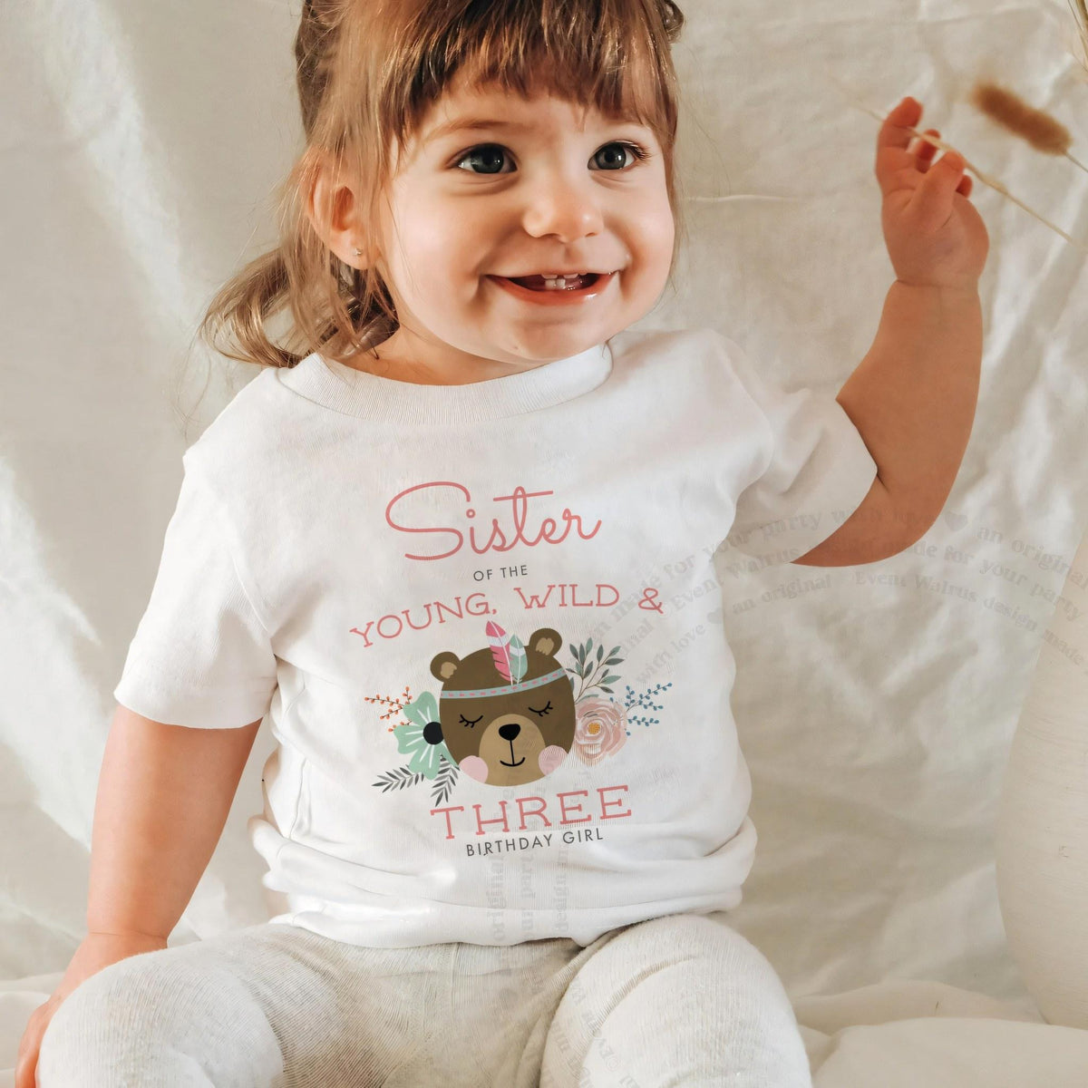 Laughing baby girl in a white Sister of the Young, Wild and Three baby tee.