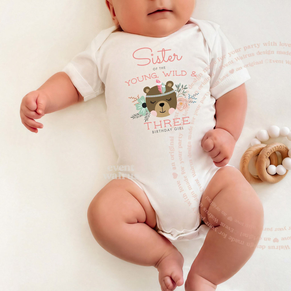 Baby lying on a white blanket in a Sister of the Young, Wild and Three bodysuit.