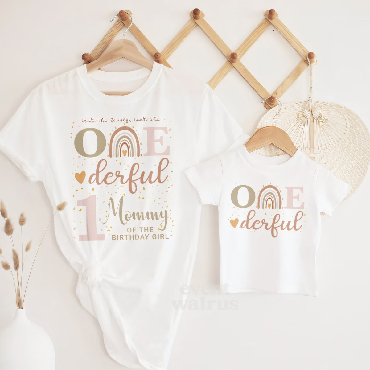Baby Onederful tee and Mommy shirt hanging together on a wooden peg rail.